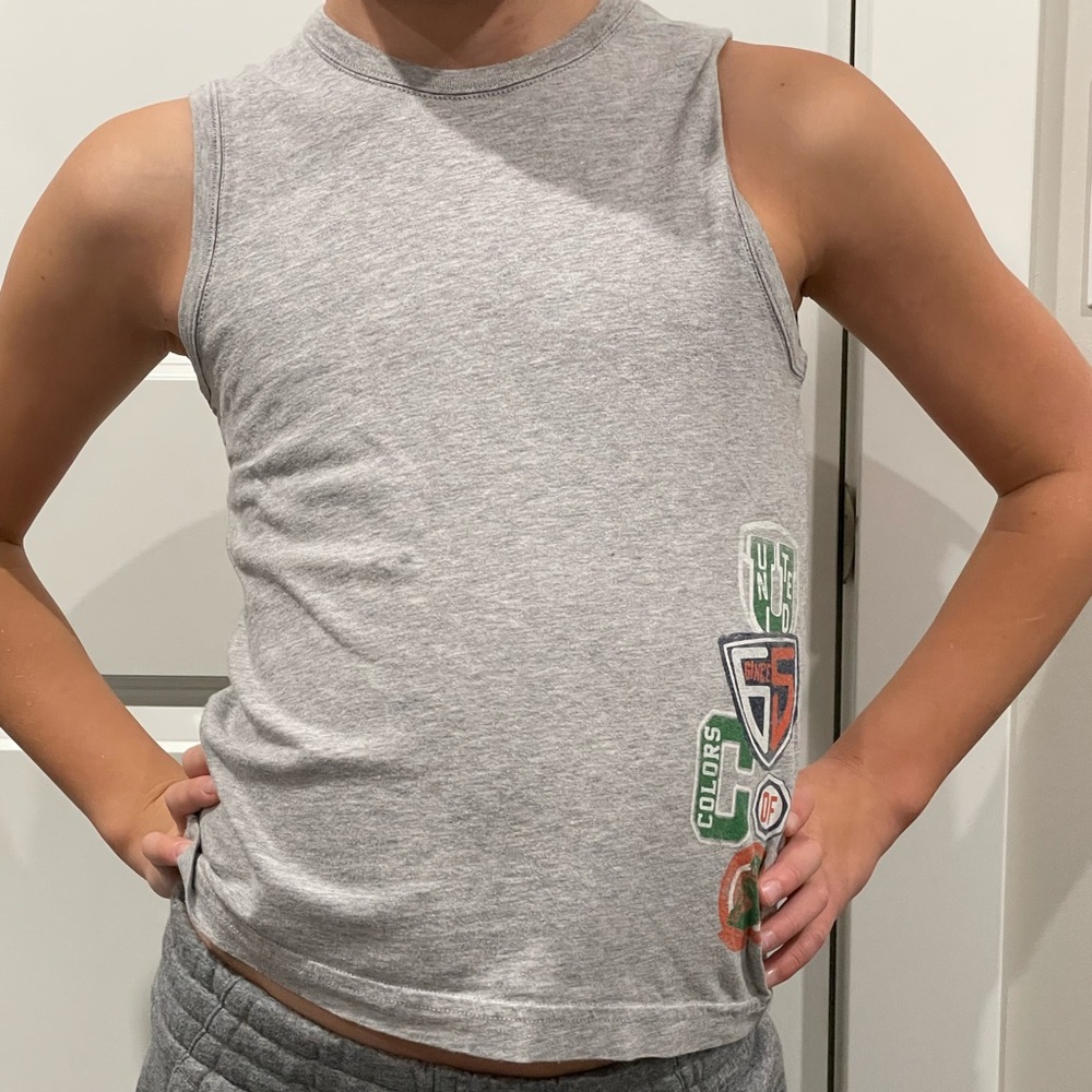 Grey shirt with little drawing on the side that are green and orange.